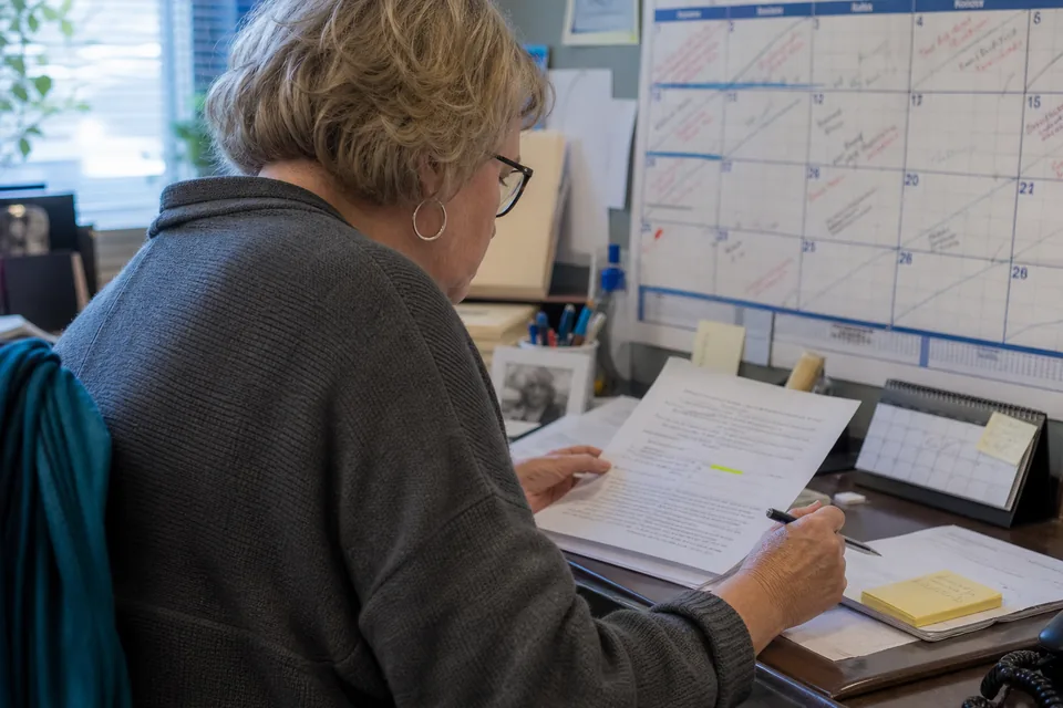 Docketing clerk comparing a court order date with a wall calendar of court dates