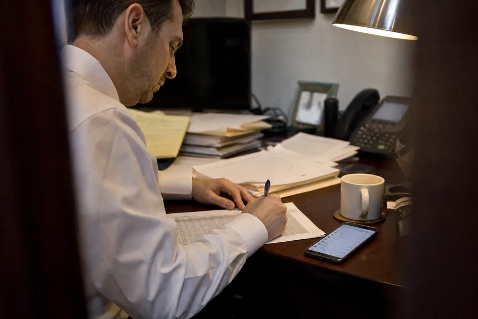 Attorney writing time entries on a printed timesheet at the end of the day